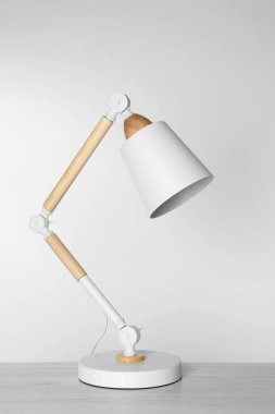 Stylish modern desk lamp on white wooden table