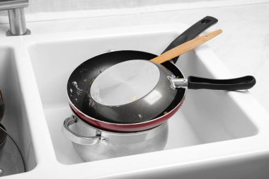 Stack of dirty kitchenware in white sink