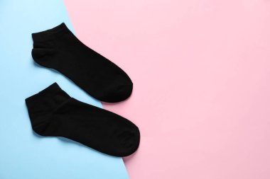 Pair of black socks on colorful background, flat lay. Space for text