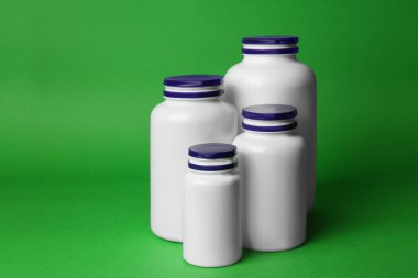 Many different plastic medicine bottles on green background. Medicament