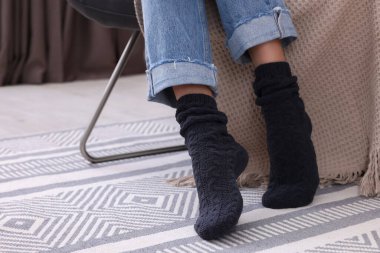 Woman wearing warm knitted socks at home, closeup
