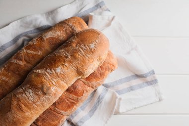 Fresh crispy ciabattas on white wooden table, top view. Space for text