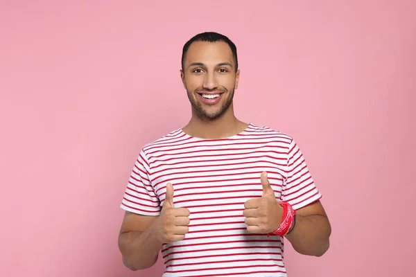 Happy African American man showing thumbs up on pink background