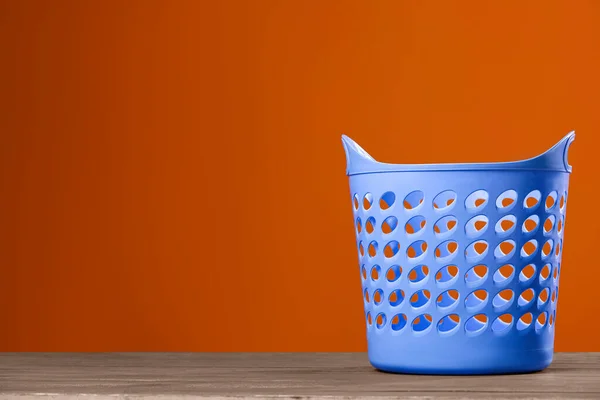 Empty plastic laundry basket near brown wall. Space for text