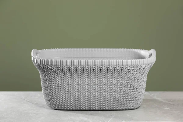 Empty plastic laundry basket near light green wall