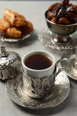 Tea, baklava dessert and date fruits served in vintage tea set on grey table, closeup. Space for text
