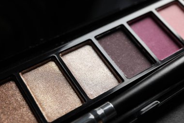 Beautiful eye shadow palette with brush on dark grey table, closeup