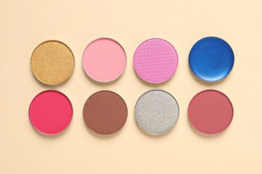 Different beautiful eye shadows on beige background, flat lay