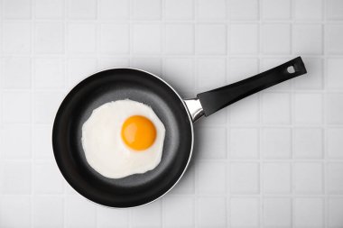 Tasty fried egg in pan on white table, top view