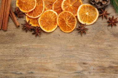 Dry orange slices, cinnamon sticks and anise stars on wooden table, flat lay with space for text