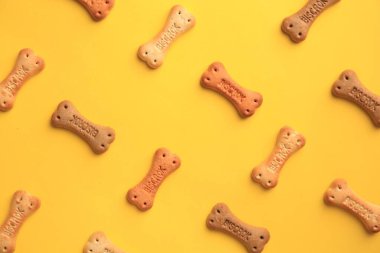 Bone shaped dog cookies on yellow background, flat lay