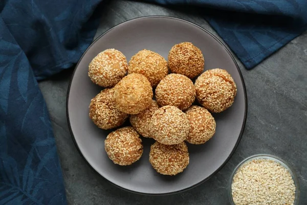 Delicious sesame balls on grey table, flat lay