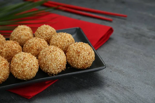 Many delicious sesame balls on black table, closeup. Space for text