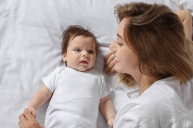 Mother calming crying daughter on bed, top view