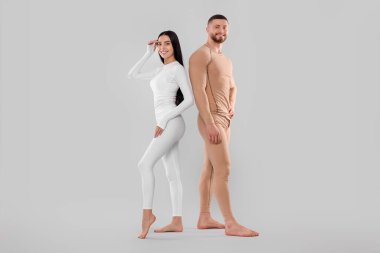 Man and woman in warm thermal underwear on light background