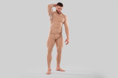 Man in warm thermal underwear on light background. Space for text