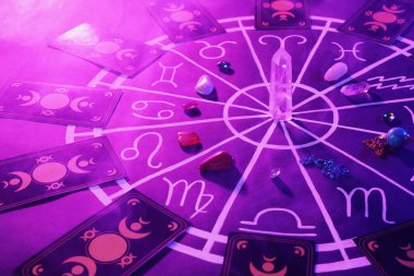 Zodyak işaretleri için doğal taşlar, tarot kartları ve mor arka planda astroloji çizelgesi. Renk tonu etkisi