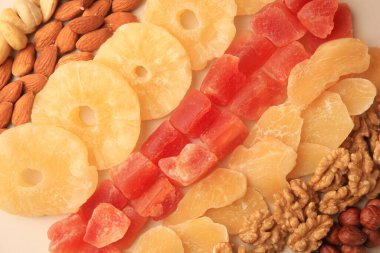 Bej arka planda farklı lezzetli fındıklar ve kurutulmuş meyveler.