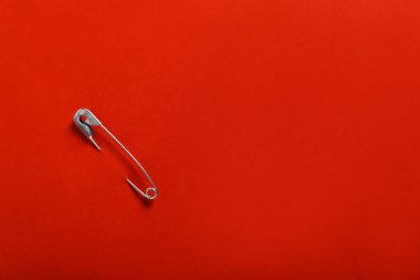 Kırmızı kağıda iliştirilmiş güvenlik iğnesi, üst manzara. Metin için boşluk