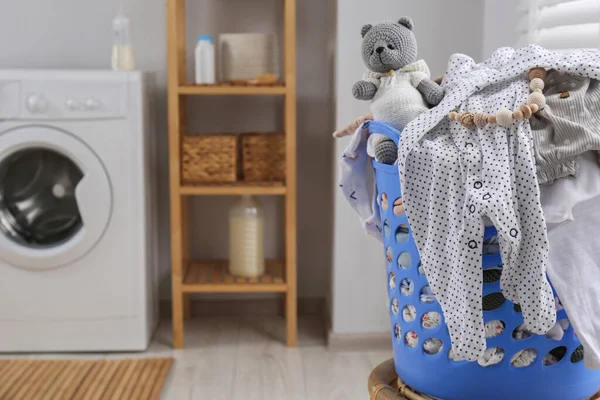 Laundry basket with baby clothes, shoes and crochet toy in bathroom, space for text