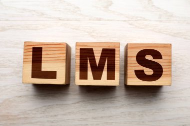 Learning management system. Cubes with abbreviation LMS on wooden background, top view