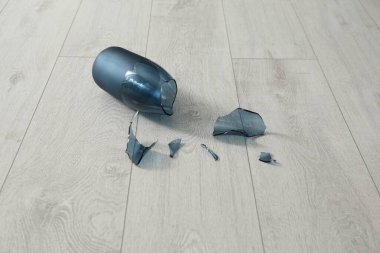 Broken blue glass vase on wooden floor