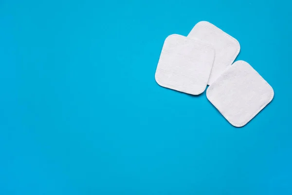 Cotton pads on light blue background, flat lay. Space for text