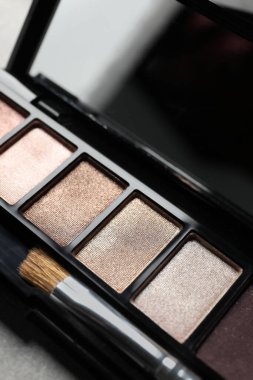 Beautiful eye shadow palette with brush on grey textured table, closeup