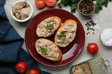 Tasty sandwiches with cod liver and different products on light grey table, flat lay