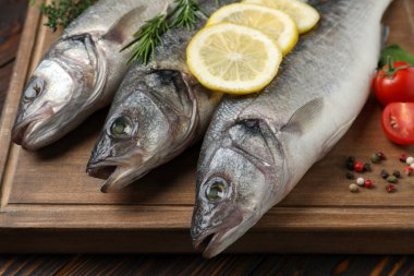 Levrek balığı ve malzemeler ahşap masada, yakın plan.