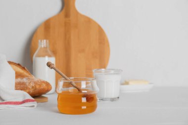 Jar with honey, milk, butter and bread served for breakfast on table. Space for text