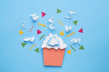 Kağıtlı kek ve açık mavi arka planda konfeti.