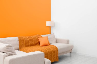 Stylish room with cosy sofa near orange wall. Interior design