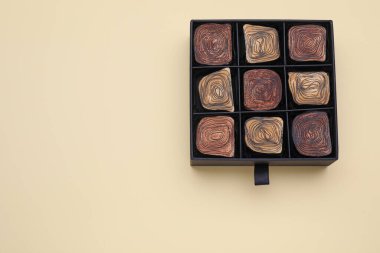 Box of tasty chocolate candies on beige background, top view. Space for text