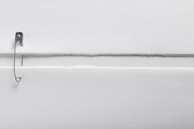 Pieces of paper sheets joined with safety pin on white background, top view