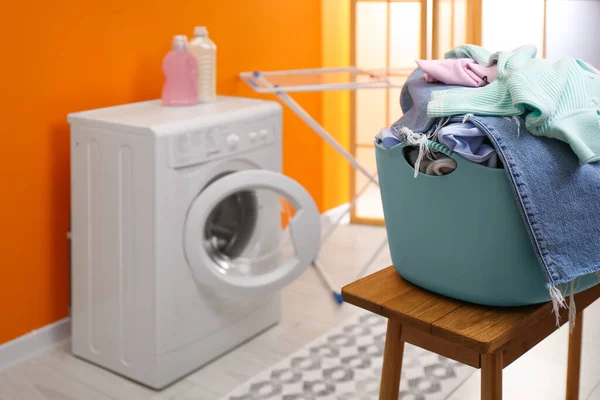 Laundry basket filled with clothes on bench in bathroom. Space for text
