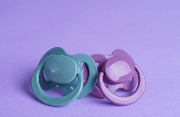 stock image New baby pacifiers on purple background, closeup