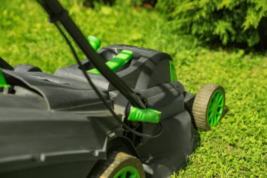 Lawn mower on green grass in garden, closeup