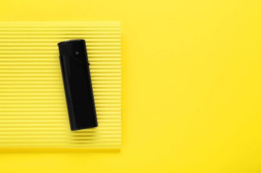 Stylish small pocket lighter with corrugated fiberboard on yellow background, top view. Space for text