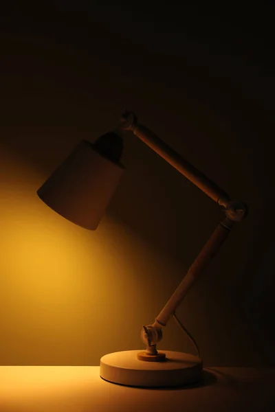 Stylish modern desk lamp on table at night