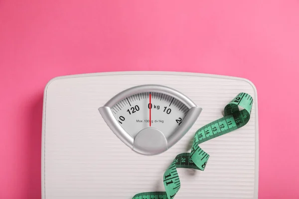 stock image Weight loss concept. Scales and measuring tape on pink background, top view. Space for text