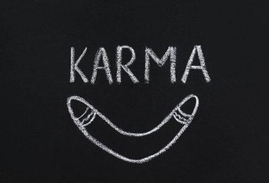 Drawn boomerang and word Karma written on blackboard