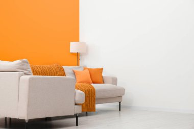 Stylish room with cosy sofa near orange wall. Interior design