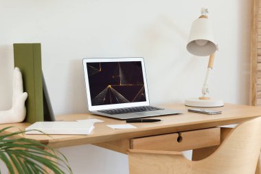 Cozy workspace with modern laptop on desk and comfortable chair at home