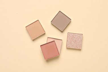 Different beautiful eye shadows on beige background, flat lay