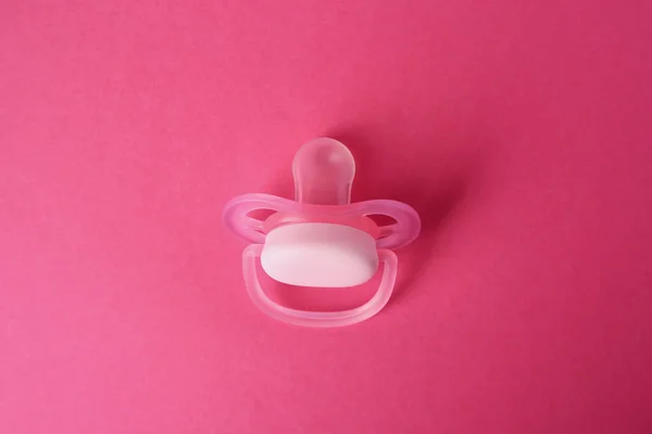 One baby pacifier on pink background, above view