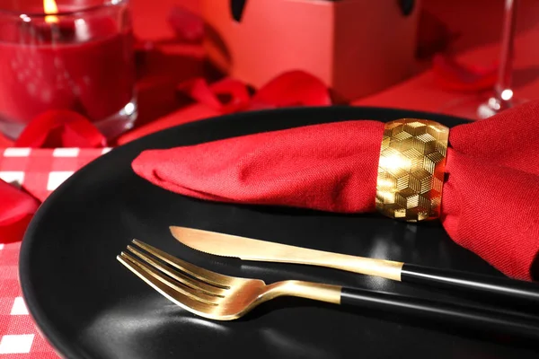 plate with cutlery and burning candle on red table for romantic dinner, closeup