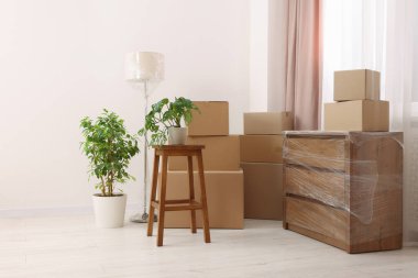 Boxes, lamp and chest of drawers wrapped in stretch film indoors