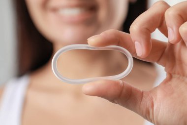 Woman holding diaphragm vaginal contraceptive ring on blurred background, closeup