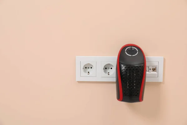 Modern compact electric heater charging from socket indoors, space for text